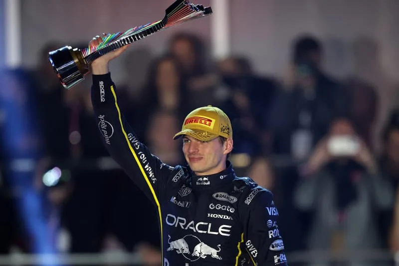 Coureur automobile avec trophée et casquette de vainqueur.