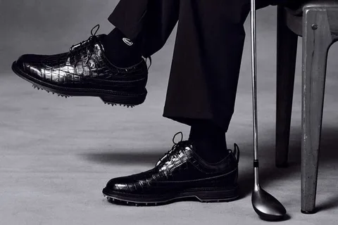 Chaussures de golf élégantes, homme assis avec un club.