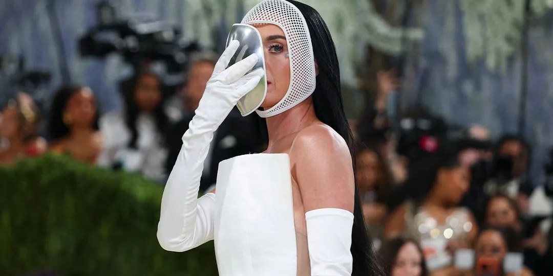 Personne en robe blanche avec masque argenté couvrant le visage.