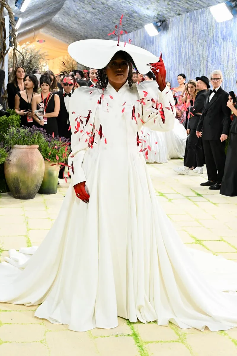 Personne en robe blanche avec chapeau large à un événement formel