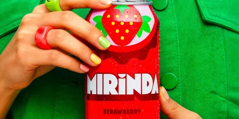 Canette de boisson Mirinda saveur fraise avec des ongles colorés.