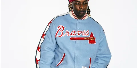 Homme avec veste bleue 'Braves' et bandana rouge sur fond blanc.