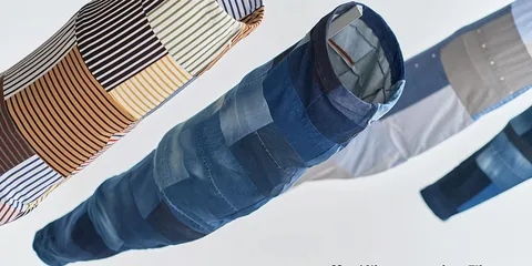 Patchwork de tissus suspendus, formes allongées, couleurs variées de denim et rayures.