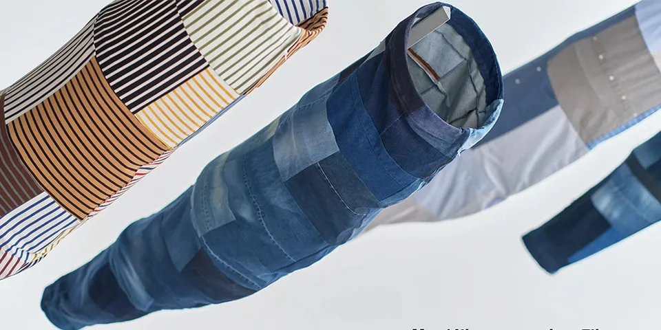 Patchwork de tissus suspendus, formes allongées, couleurs variées de denim et rayures.