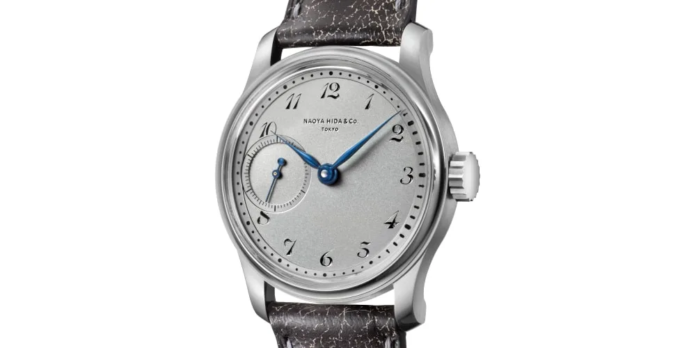 Montre-bracelet élégante avec cadran gris et aiguilles bleues.