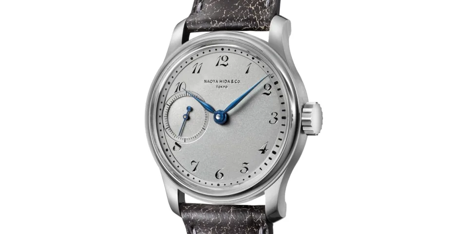 Montre-bracelet élégante avec cadran gris et aiguilles bleues.