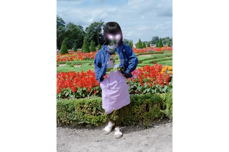 Enfant dans un jardin fleuri avec visage flou et vêtements colorés.