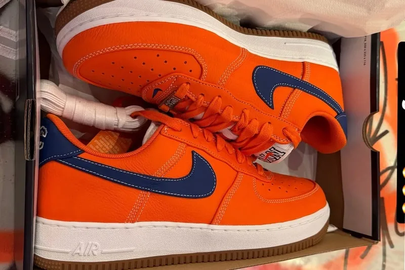Chaussures orange avec Swoosh bleu en boîte ouverte.
