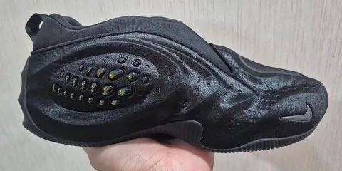 Basket noire avec motif texturé et détails irisés, tenue en main gauche.