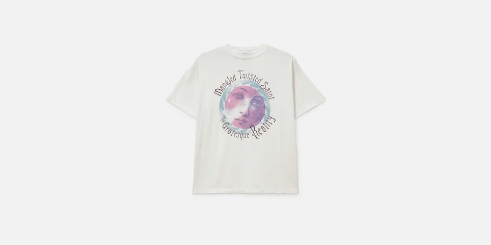 T-shirt blanc avec un visage artistique et texte imprimé.