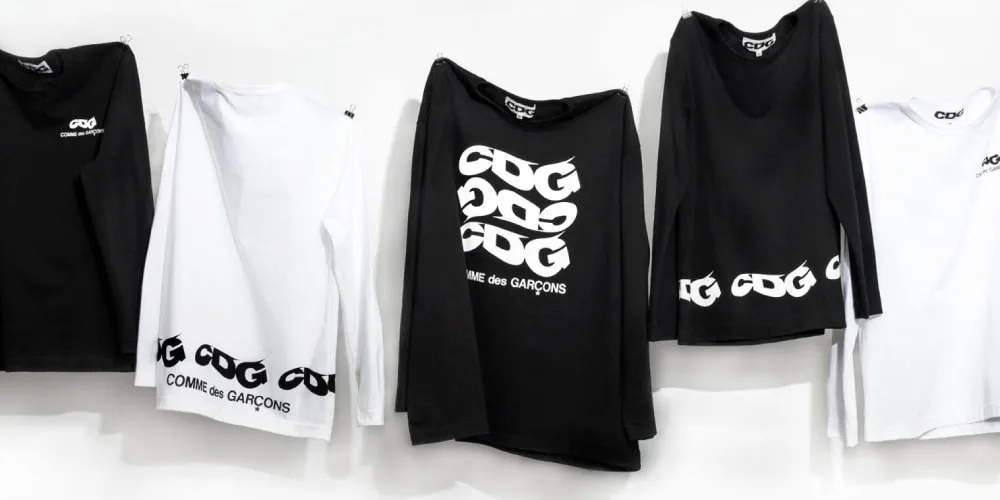 Cinq t-shirts CDG noirs et blancs sur fond blanc.