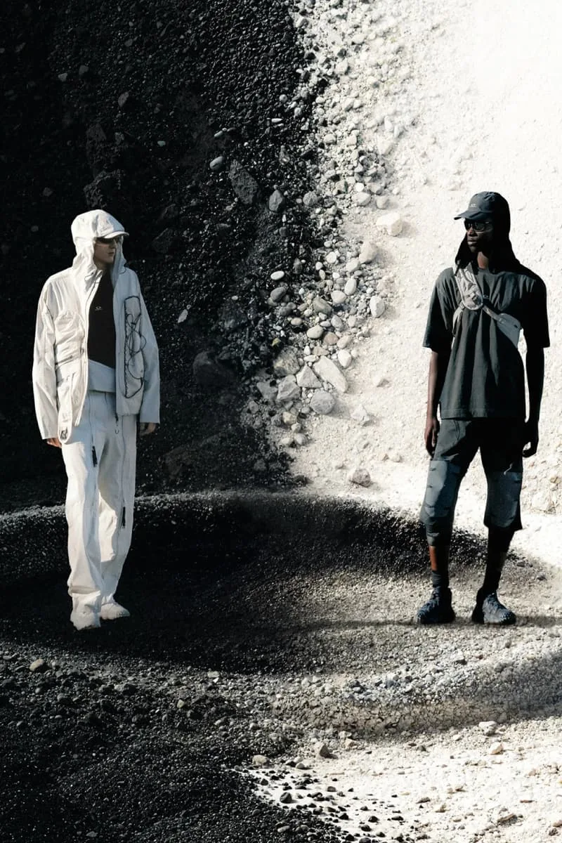 Deux personnes en vêtements modernes devant un fond noir et blanc.