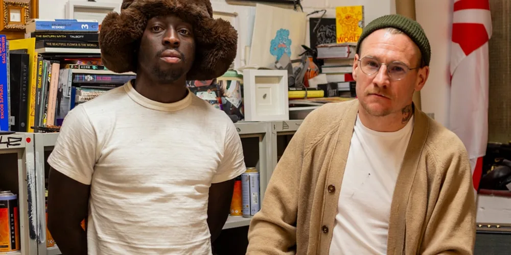 Deux hommes dans un bureau avec des livres en arrière-plan.