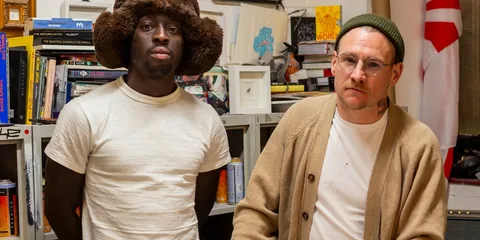 Deux hommes dans un bureau avec des livres en arrière-plan.