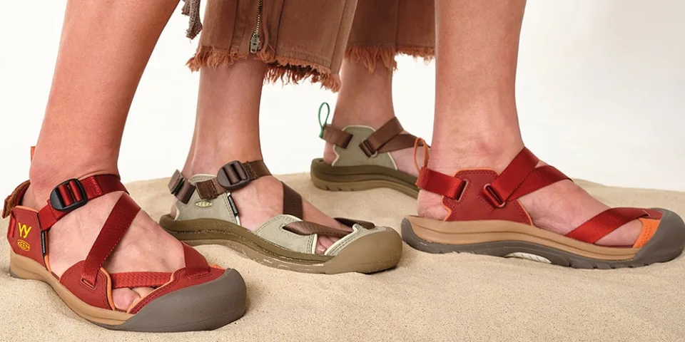 Personnes portant des sandales colorées sur le sable.