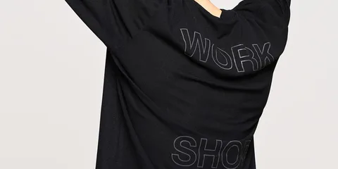 Personne portant un t-shirt noir avec 'WORK SHOP' écrit dessus, de dos.