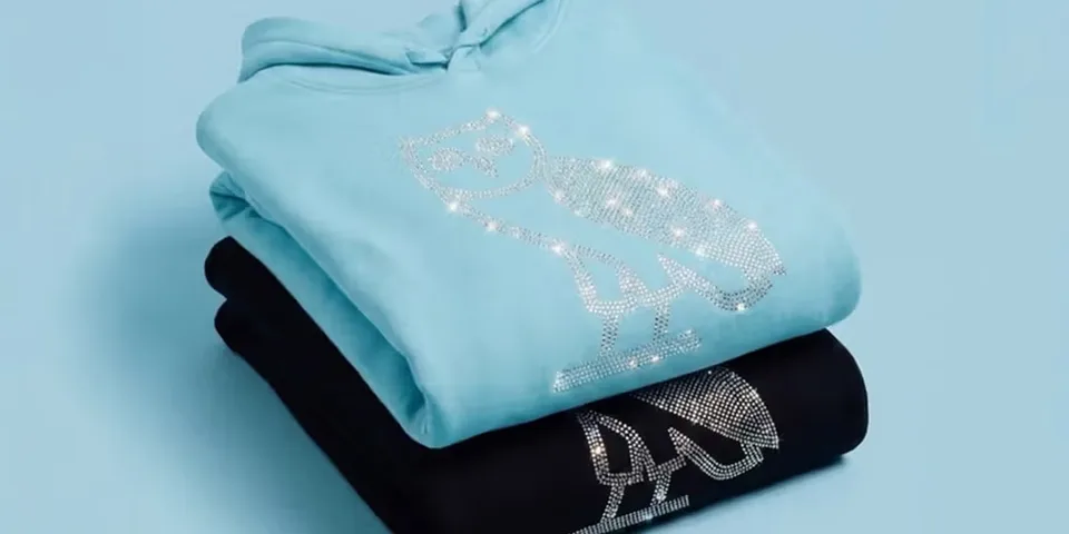 Deux sweats empilés avec motif hibou en strass, bleu clair et noir.