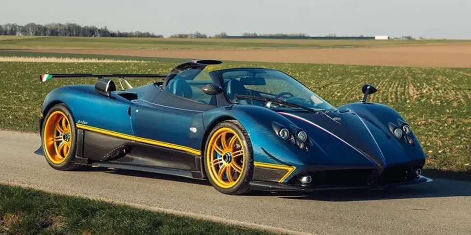 Voiture de sport bleue avec jantes jaunes sur route champêtre