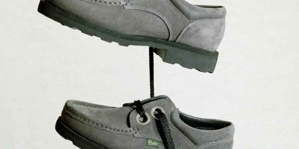 Deux chaussures grises en apesanteur, reliées par un lacet noir.