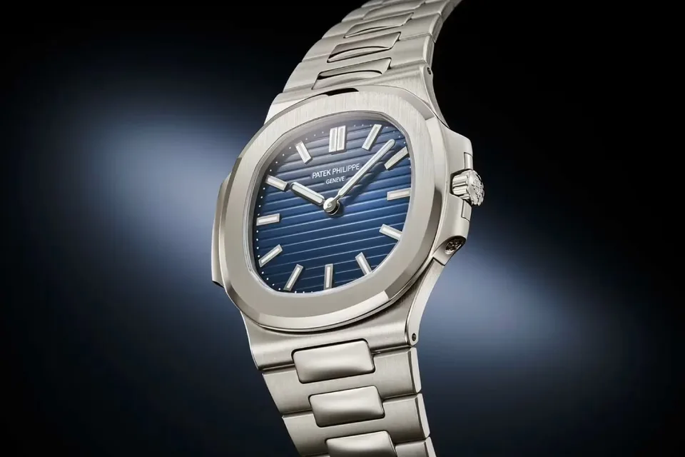 Montre argentée avec cadran bleu sur fond dégradé.