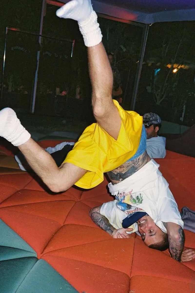 Personne en équilibre sur la tête, portant un short jaune et des chaussettes blanches.