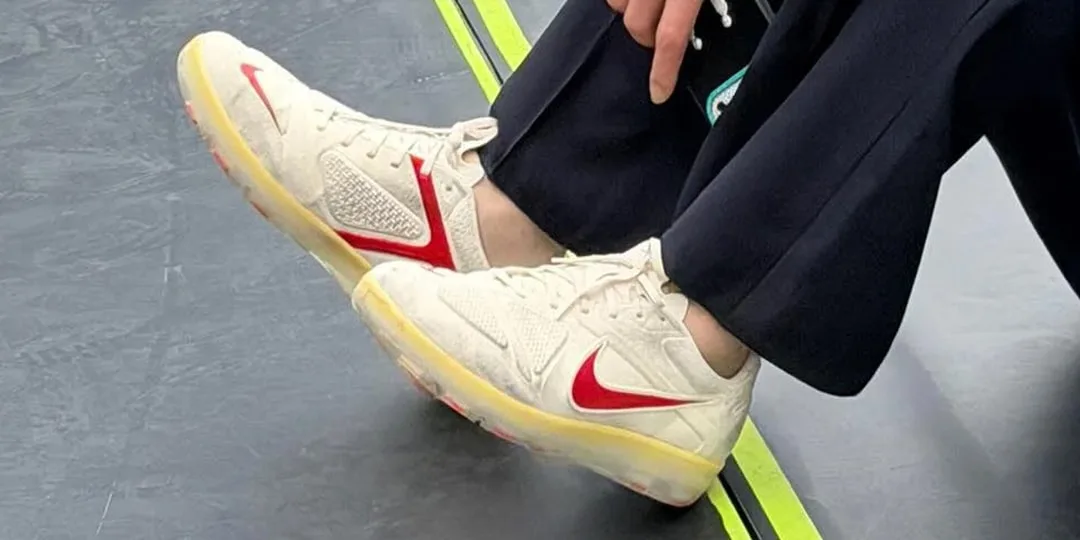 Paire de baskets blanches avec logo rouge sur le côté.