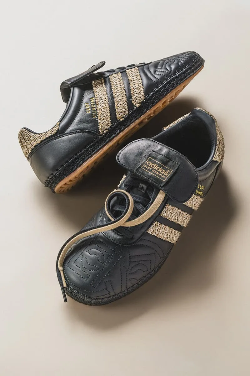 Chaussures noires et dorées de marque adidas sur fond beige.