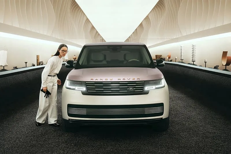 Femme posant devant un Range Rover dans un espace moderne et élégant.