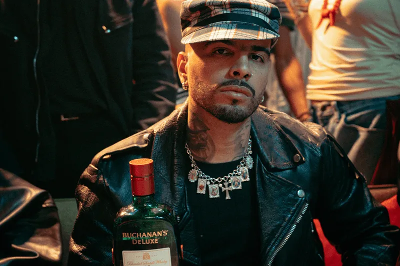Homme en blouson cuir avec bouteille de whisky Buchanan's.