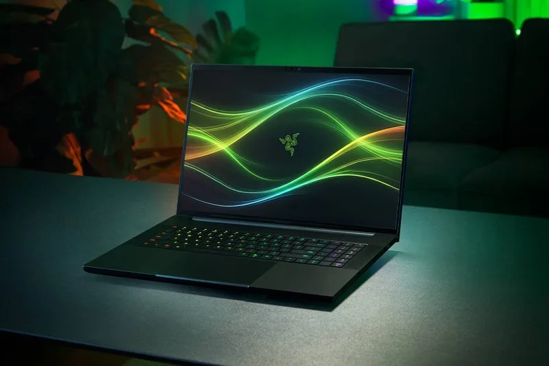 Ordinateur portable sur une table avec écran allumé, ambiance lumineuse verte.