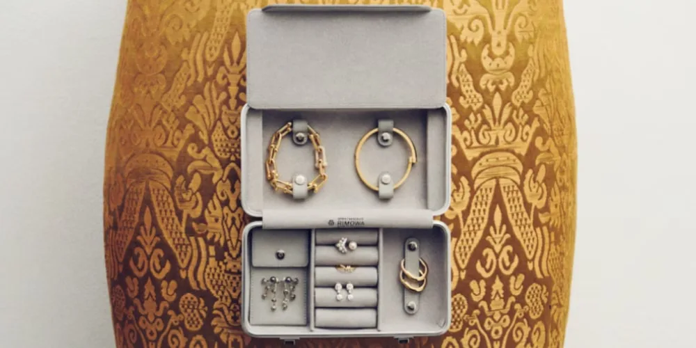 Boîte à bijoux ouverte avec bracelets et boucles d'oreilles sur fond orné.