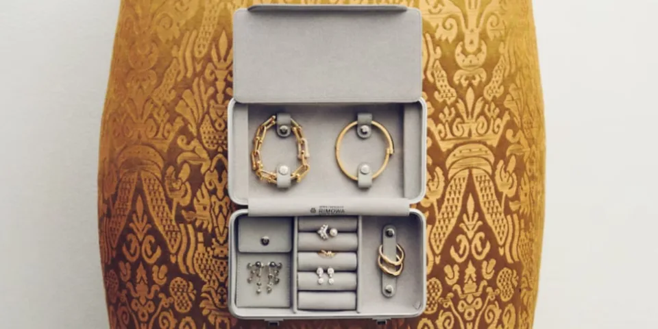 Boîte à bijoux ouverte avec bracelets et boucles d'oreilles sur fond orné.