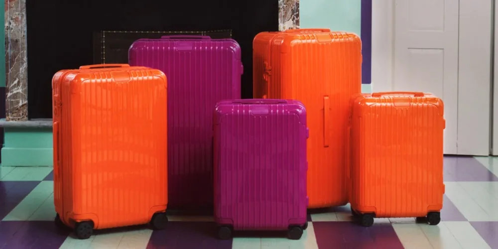 Ensemble de valises colorées orange et violettes sur un sol à rayures.