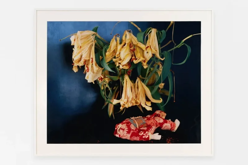 Des fleurs fanées avec une petite poupée en kimono rouge en dessous.
