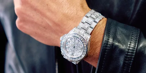 Main portant une montre en argent étincelante avec bracelet métallique.