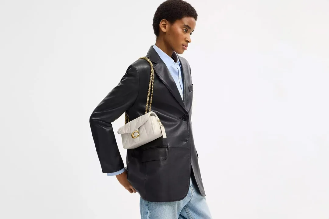 Personne portant un blazer noir et un sac blanc.