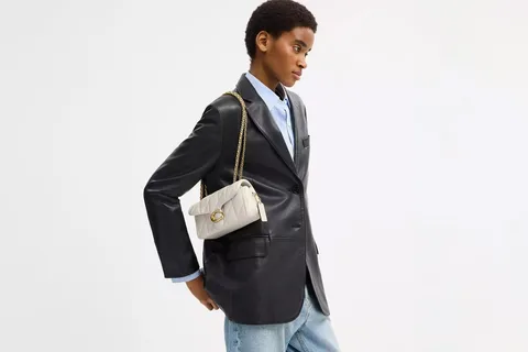 Personne portant un blazer noir et un sac blanc.