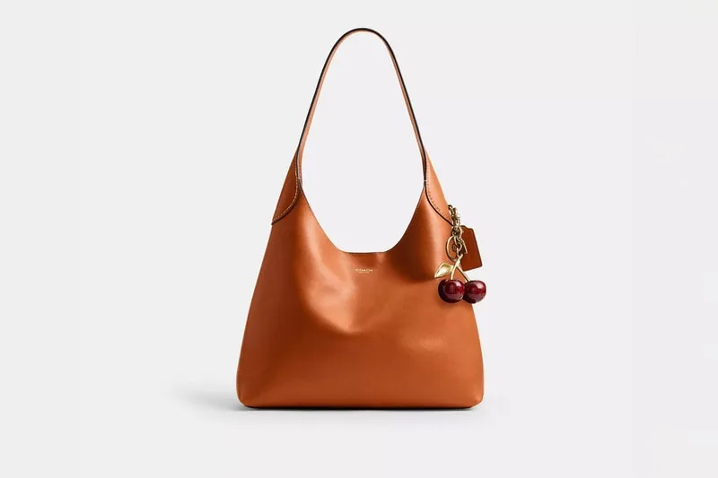Sac à main en cuir marron avec pendentif cerises rouges et dorées.