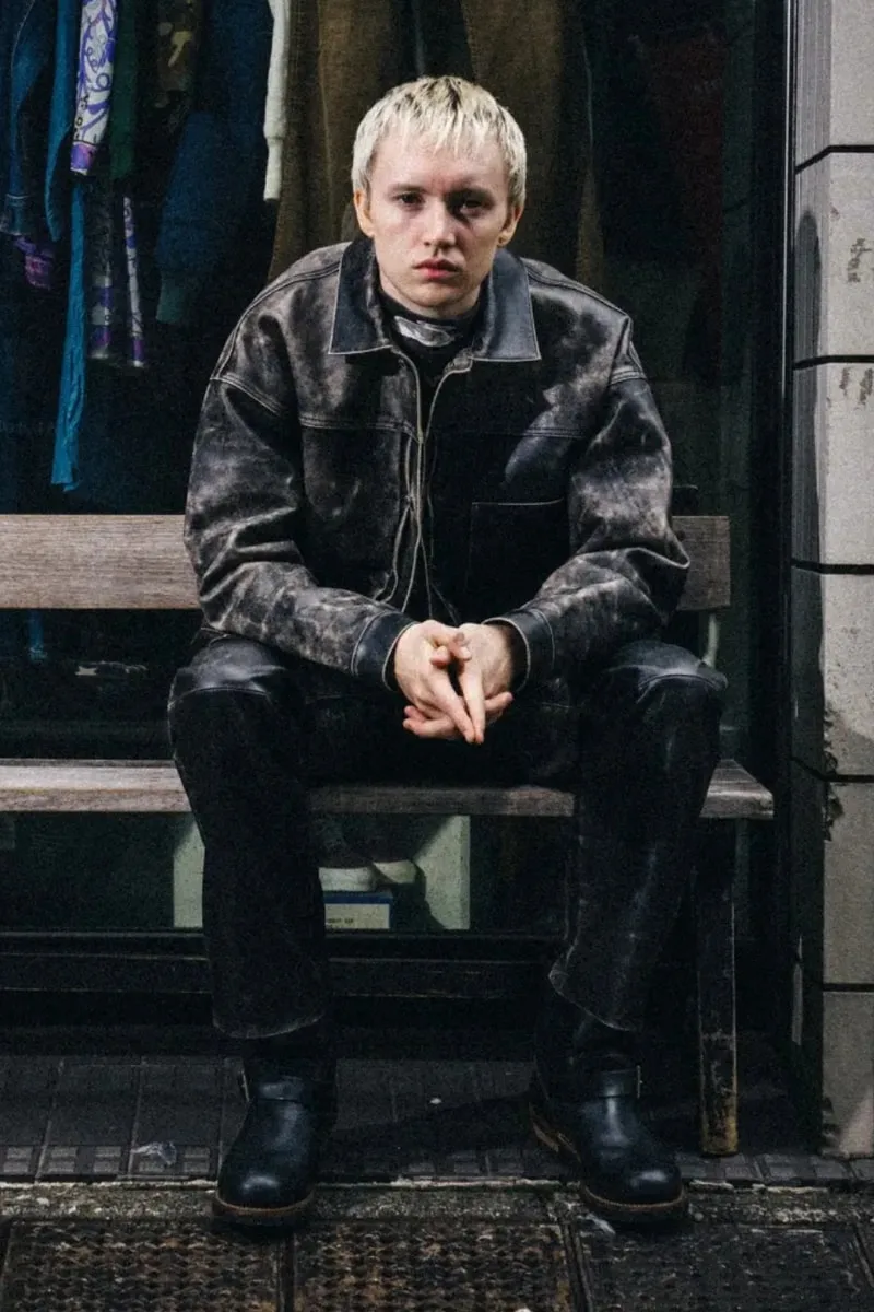 Personne assise en vêtements en cuir, regardant vers l'avant.