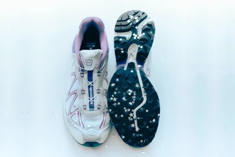 Chaussure de sport blanche avec semelle étoilée et intérieur violet.