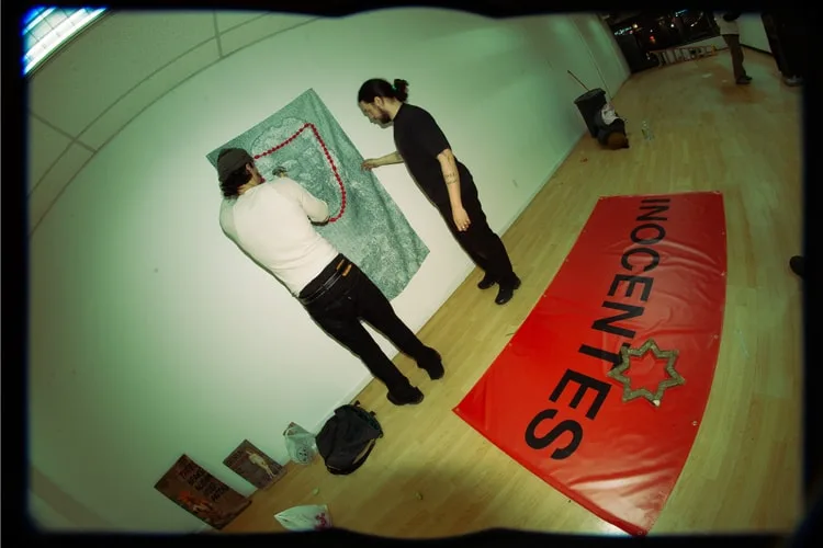 Deux hommes installant une bannière rouge sur un mur blanc.