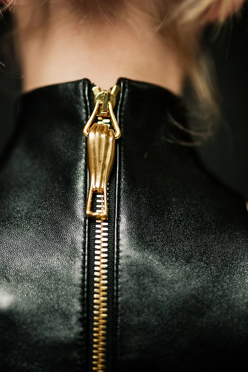 Fermeture éclair dorée sur un vêtement en cuir noir.