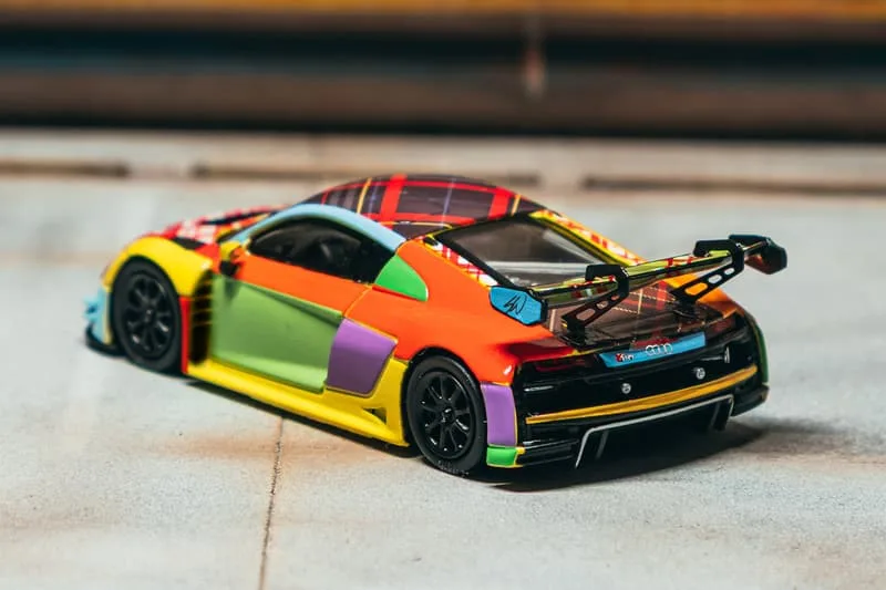Modèle réduit de voiture de course multicolore sur une surface grise.