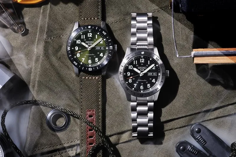 Deux montres Seiko sur une surface textile avec des accessoires.
