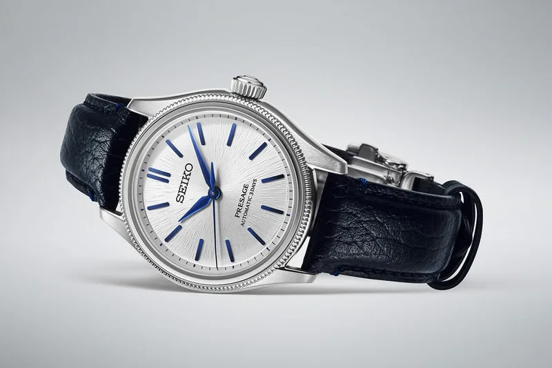 Montre Seiko avec bracelet en cuir noir et cadran argenté.