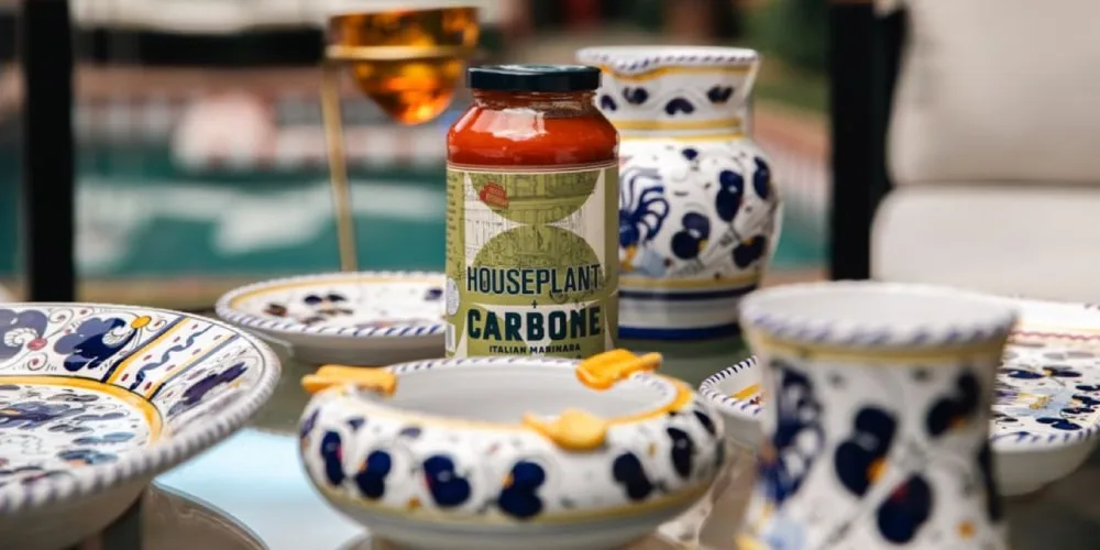 Pot de sauce Carbone sur table avec vaisselle ornée de motifs colorés.