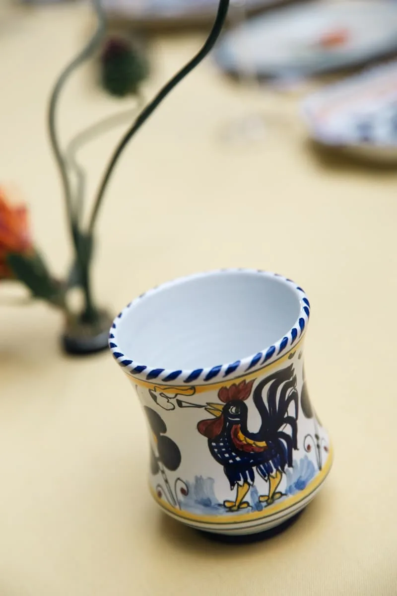 Verre décoratif avec motif de coq sur table avec nappe jaune.