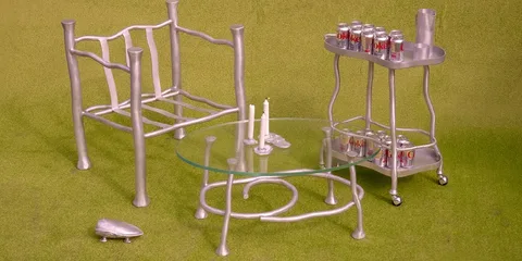 Mobilier en aluminium avec canettes de soda sur un chariot à roulettes, fond vert.