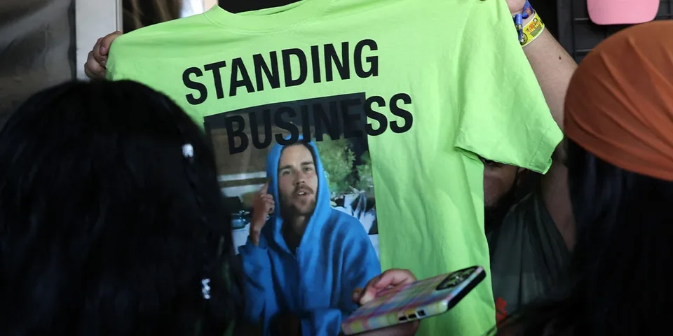 T-shirt vert avec photo et texte 'Standing Business' en noir.