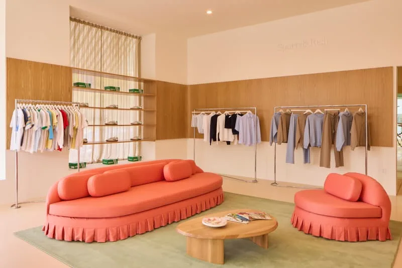 Salon avec meubles roses et vêtements sur des portants